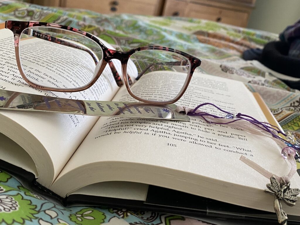 A photo of a book with a pair of eyeglasses and a bookmark on it